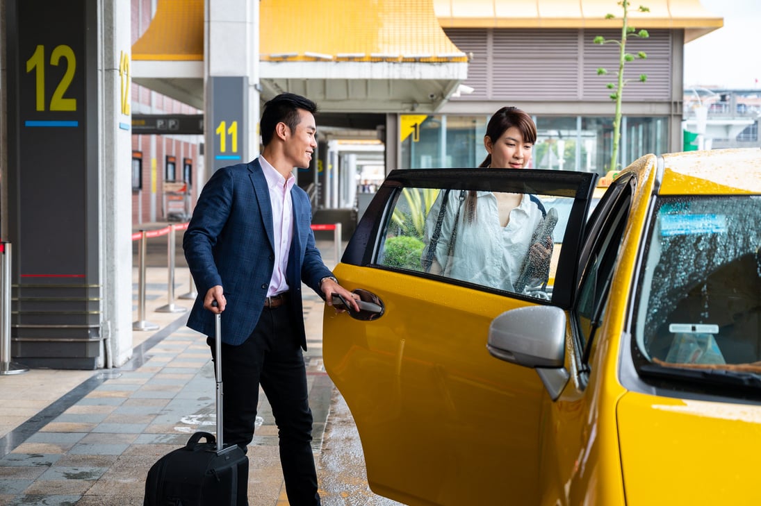 Business couple entering taxi at airport